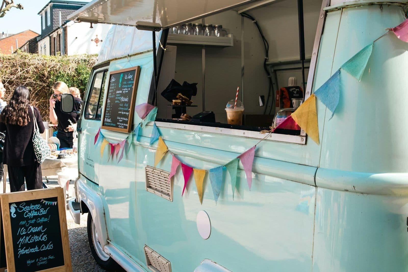 Hellblauer Foodtruck mit offener Ausgabeklappe auf einem Parkplatz